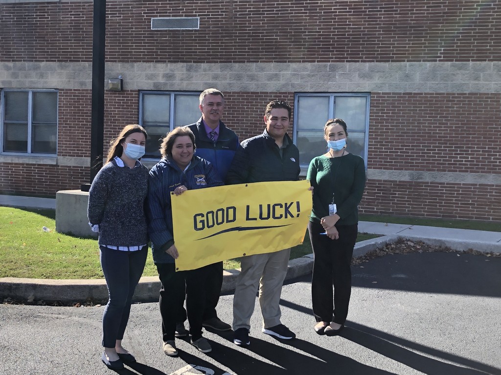 Staff members holding Good Luck sign